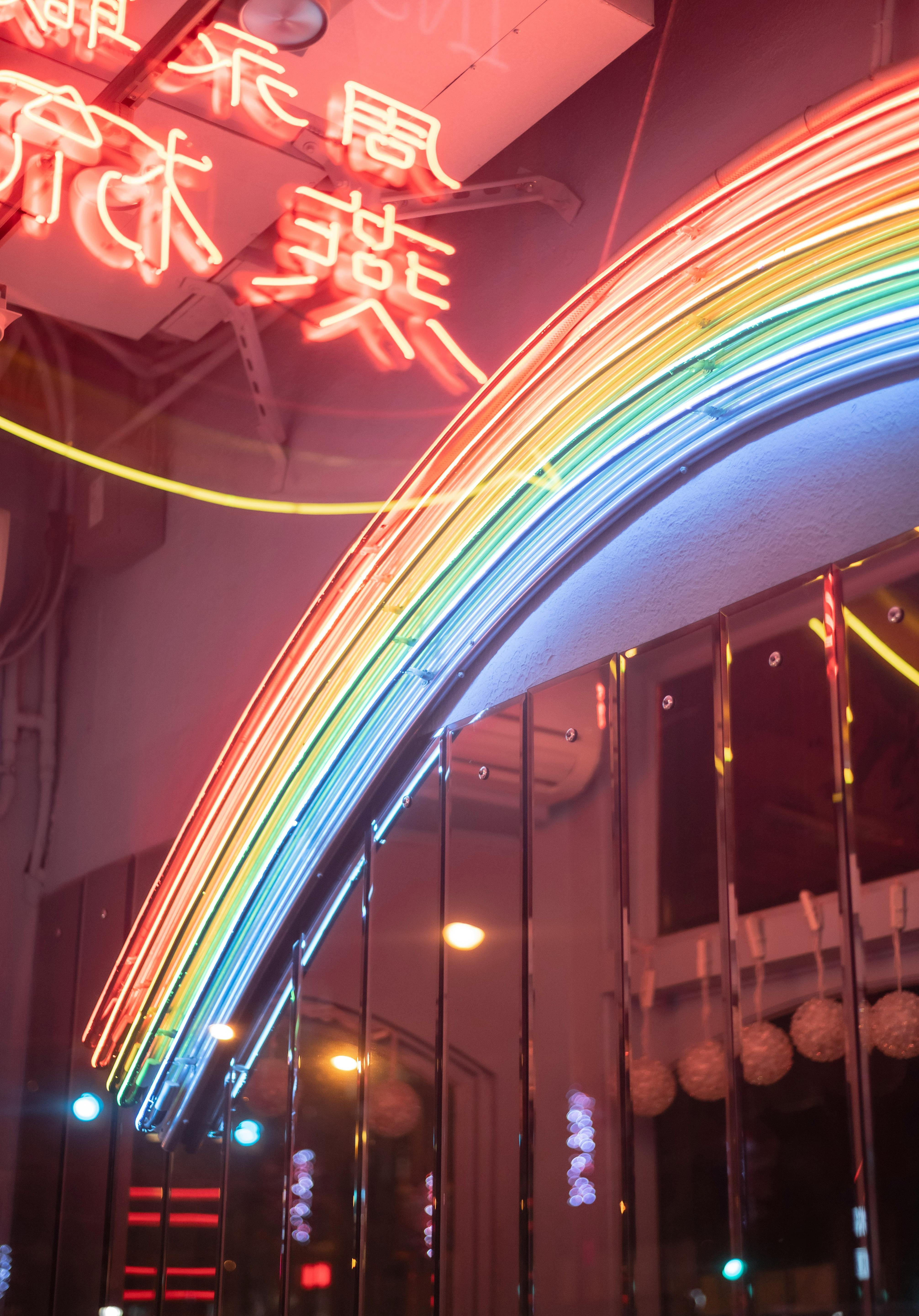 Neon rainbow arch with Chinese characters above a building at night.