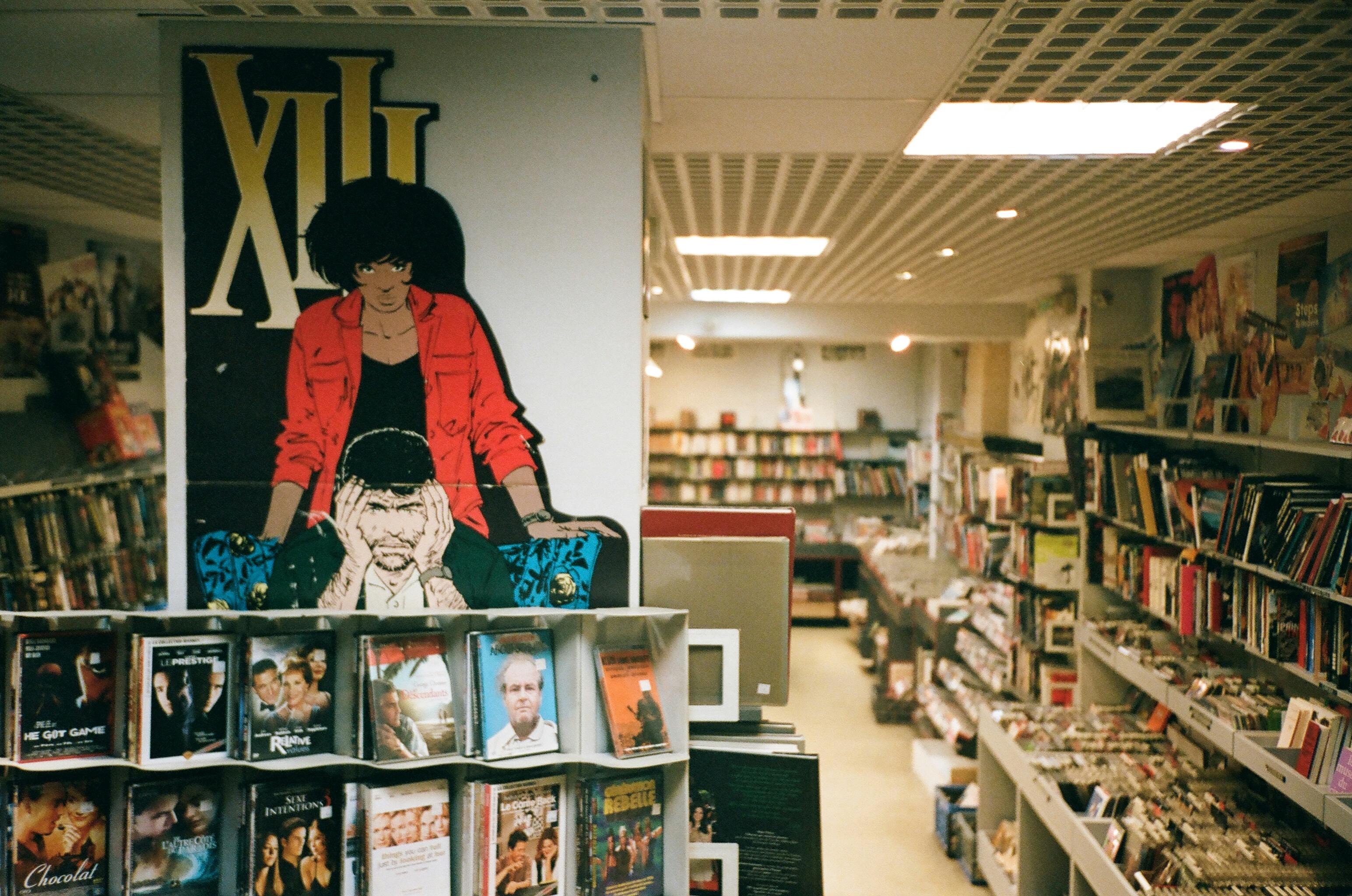 Interior of a music store with shelves stocked with CDs and a large poster on the wall.