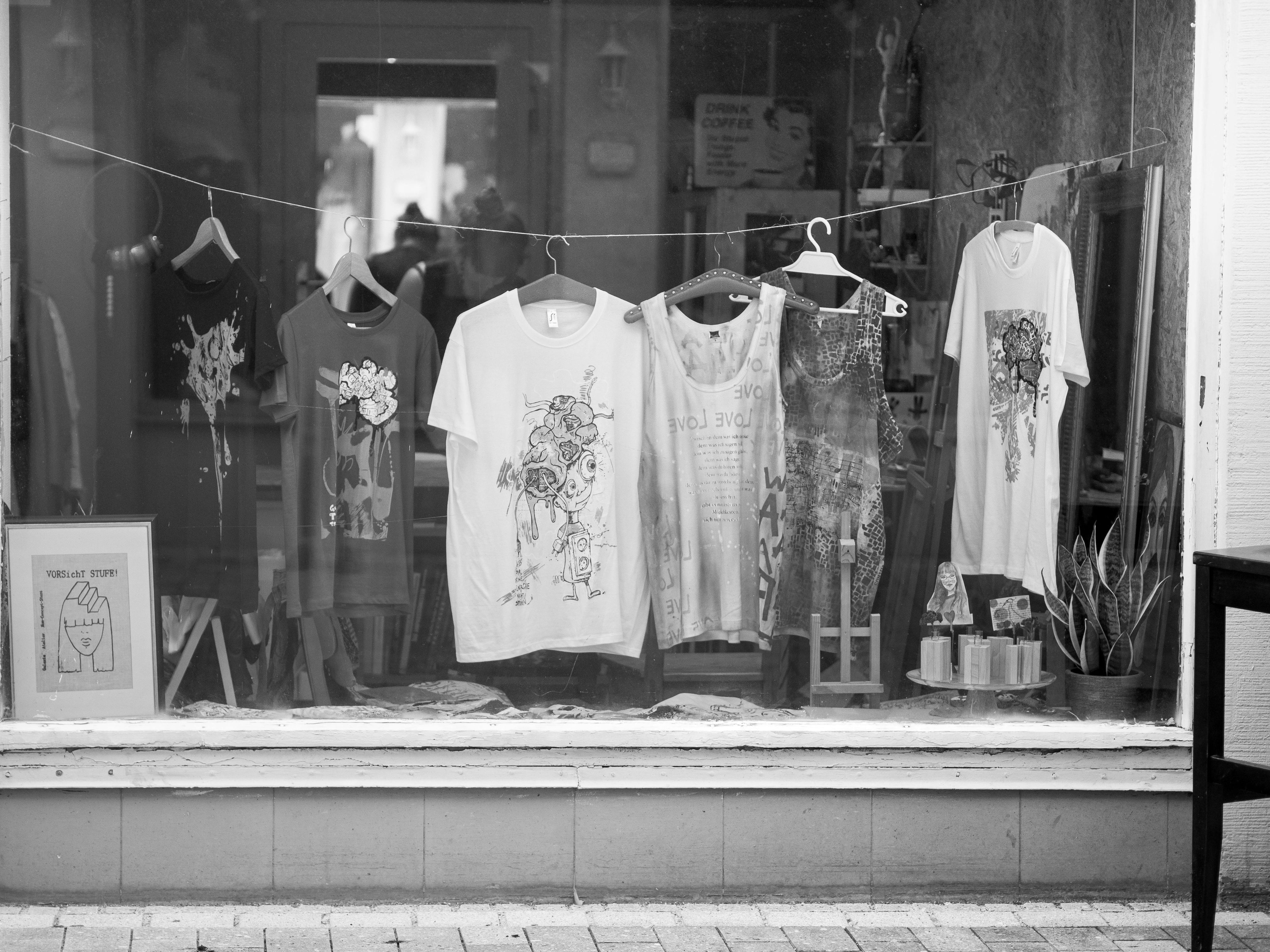 a black and white photo of several screen printed tops hanging in a shop window
